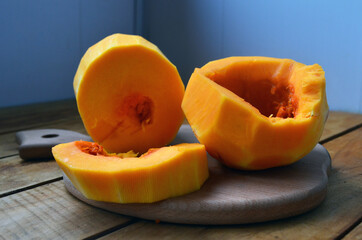 Sliced ​​orange pumpkin on a wooden board. Fresh vegetables without skin. Pieces.