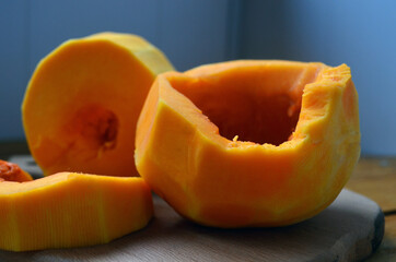 Sliced ​​orange pumpkin on a wooden board. Fresh vegetables without skin. Pieces.