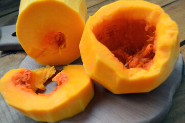 Sliced ​​orange pumpkin on a wooden board. Fresh vegetables without skin. Pieces.