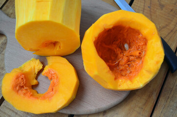 Sliced ​​orange pumpkin on a wooden board. Fresh vegetables without skin. Pieces.