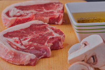 Raw pork chops with olive oil and mushrooms.