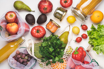 Fresh vegetables, fruits, milk, juice, pasta and beans in eco cotton bags, glass jars on white table. Zero Waste Food Shopping. Waste free life style