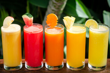 mixed fresh organic fruit juices glasses on sunny garden table