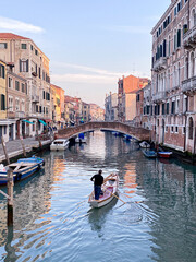 A man rowing on a typical boat in a canal of Venice