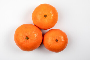 Three tangerine or mandarin fruit on a white background. Vitamins, nutrition and Christmas background