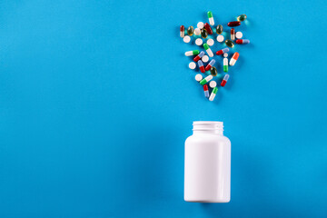 White jar with scattered pills. Uncontrolled drug use
