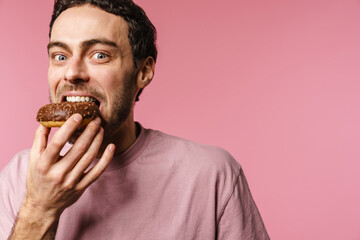 Joyful handsome hungry guy eating doughnut on camera