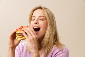 Happy beautiful hungry girl eating hamburger on camera