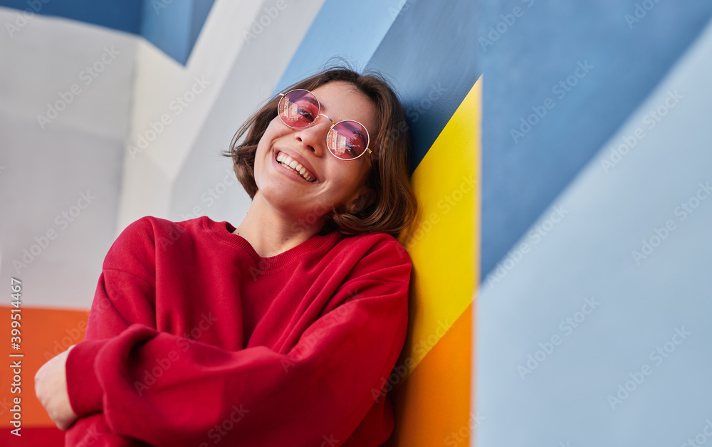 Wall mural happy female hipster leaning on colorful wall - Wall murals