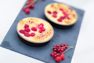 Crème brulée aux framboises et groseilles fait maison sur une ardoise noire