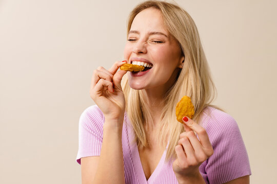 Cheerful beautiful girl laughing while eating nuggets on camera
