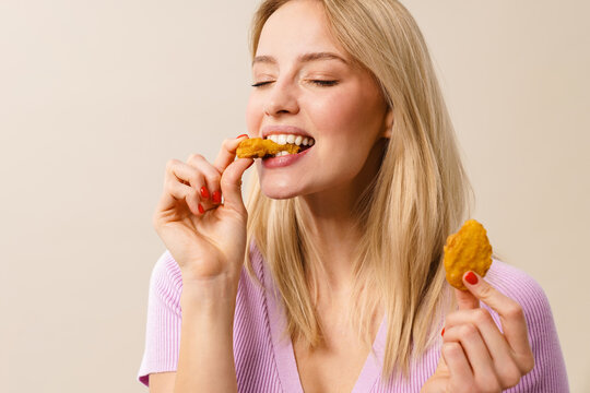 Cheerful beautiful girl smiling while eating nuggets on camera