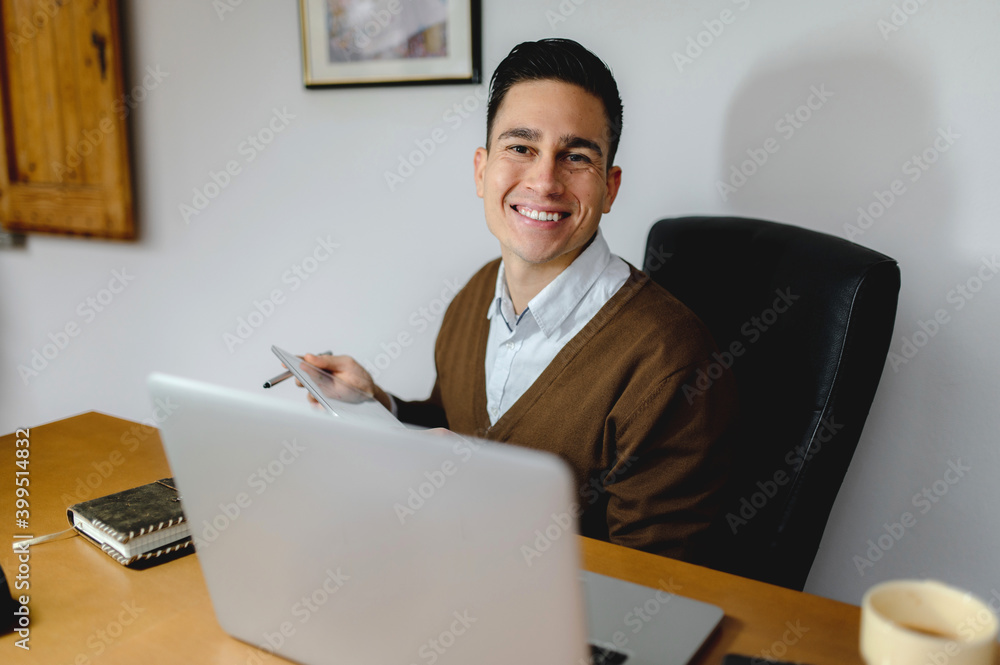 Canvas Prints Portrait of young caucasian attractive man with smiling face looking at the camera. Guy working in the office with laptop computer. Freelancer, smart working, tele working, concept.