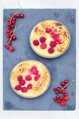 Crème brulée aux framboises et groseilles fait maison sur une ardoise noire