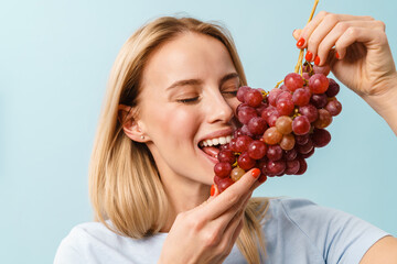 Happy charming blonde girl eating grapes on camera
