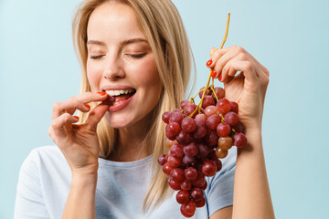 Happy charming blonde girl eating grapes on camera