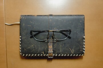 Top view leather vintage notebook with glasses. Reading, hobby, planning, personal objects concept.