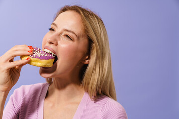 Happy charming blonde girl eating doughnut on camera