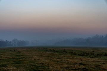 Mystical fog over farmland with mountains in the background