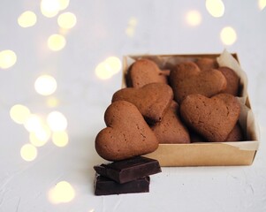 Heart-shaped cookies and chocolate on a white background. Valentine's day. The cozy backdrop of the Christmas atmosphere. Christmas lights