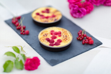 Crème brulée aux framboises et groseilles fait maison sur une ardoise noire