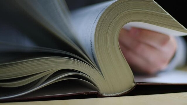 Male hand flipping through the pages of a book, closeup view