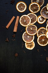 Fototapeta na wymiar Set for mulled wine on a black background, scattered dry oranges, cinnamon, cloves, star anise, with copyspace