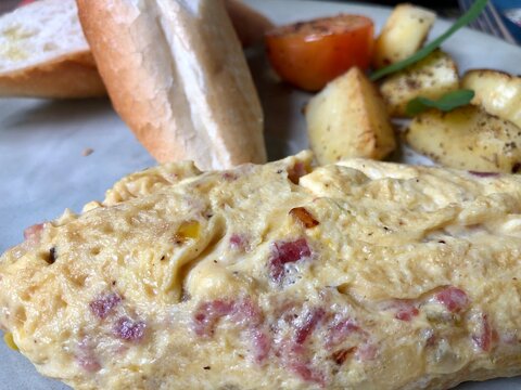 Omelette Close-up with Bread and Potatoes in Background