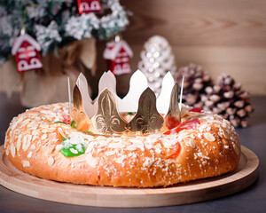 Traditional Epiphany cake Roscon de Reyes on wooden table top with small Christmas tree, wrapped gifts and decoration closeup, top view