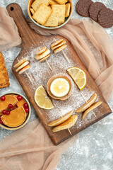 Simple pancakes with lemons on cutting board and cookies on orange towel on blue background