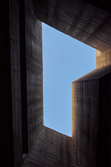 Massive concrete building overlooking the blue sky. Abstract contemporary geometric architecture....