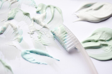 White toothbrush and toothpastes in three colors: green sweet mint, blue strong mint and white-whitening. White background, copy space. The concept of oral hygiene