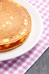 Half shot of delicious pancakes on a pink stripped towel on mixed color background vertical view