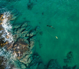 Aerial view at turquoise sea and Spearfishing diver with fool equipment and speargun hunting near rocks