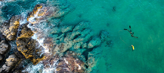 Spearfishing diver with fool equipment and speargun hunting at mediterranean sea near rocks