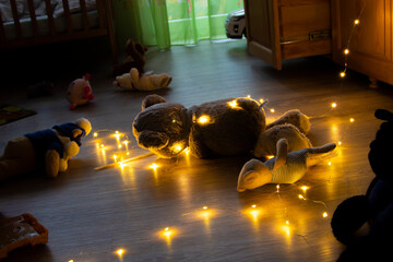 thrown stuffed toys on the floor with a glowing electric garland during winter holidays