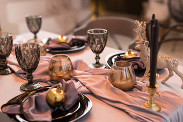 Fototapeta na wymiar Close up of festive Christmas table setting with empty wine glasses and black plate with gray napkins