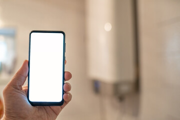 digital smart phone in hand on the blur background of water boiler
