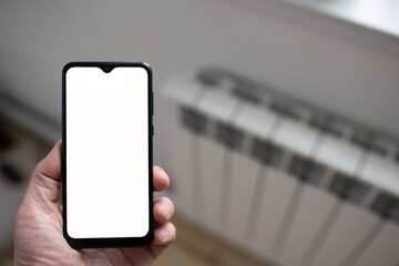 digital smart phone in hand on the blur background of heating radiator