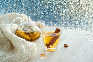 Winter warming tea with lemon and orange against the background of frosty patterns. Hot drink in a...
