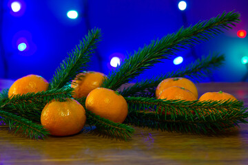 Fototapeta na wymiar tangerines with a Christmas tree and garlands in the background