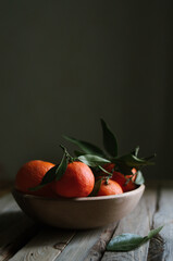Bright ripe tangerines on wooden table isolated on dark background