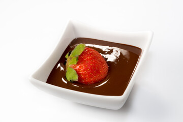 strawberry in melted chocolate inside a white ceramic cup on a white background