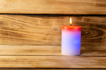 Fototapeta na wymiar Candle on a wooden background. A red and white candle that changes color when you light it Shallow depth of field.