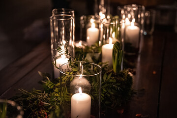 Glass jar's with burning candles ligh the room, making a romantic and warm atmosphere in retro bedroom with nice decoration in background.