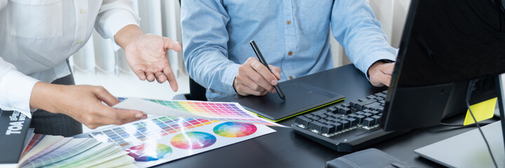 Graphic designer or creative working together coloring using graphics tablet and a stylus at desk...