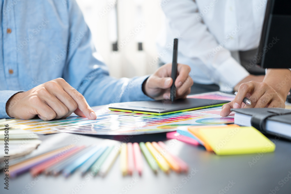 Poster graphic designer or creative working together coloring using graphics tablet and a stylus at desk wi