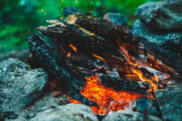 Vivid smoldered firewoods burned in fire close-up. Atmospheric background with orange flame of...