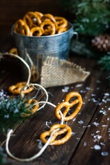 Bagels cookies with salt in metal mug on wooden background with  Christmas tree. Preparation for Christmas. Making garland of cookies and thread
