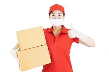 Fototapeta na wymiar Delivery postal service asian woman in red uniform isolated on white background working as courier or dealer holding and delivering package wearing red cap,medical face mask and gloves with box.